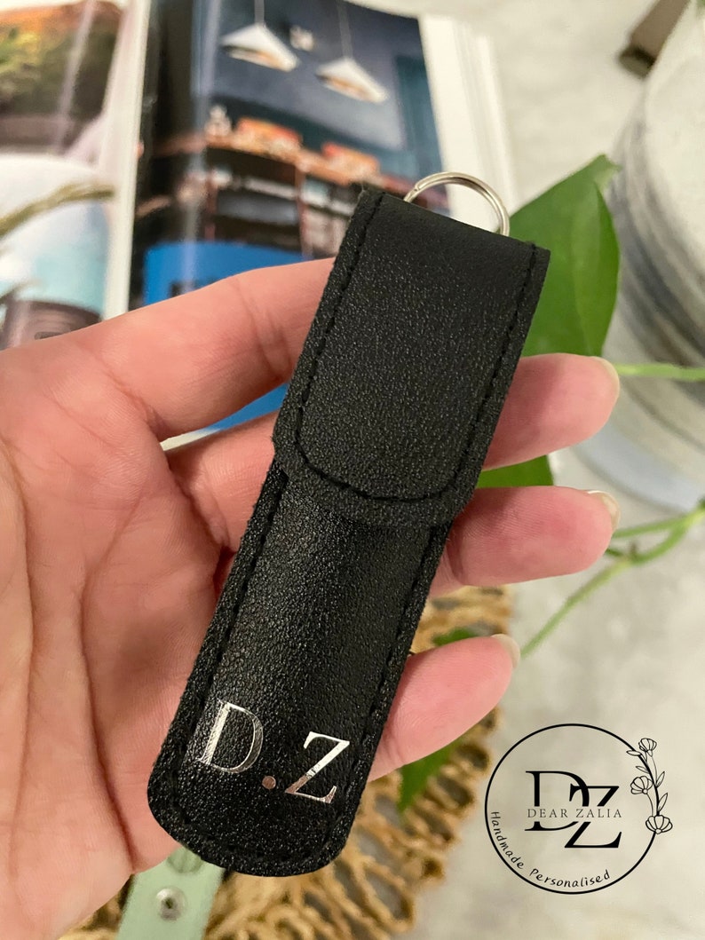 May include: Black leather keychain with a silver metal ring and the initials "D.Z." engraved in silver. The keychain is handmade and personalized.