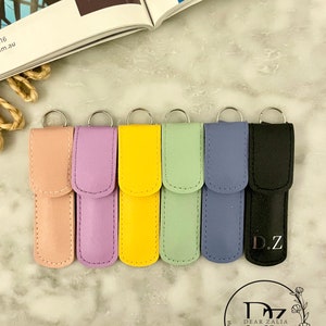 May include: Seven colorful leather keychains with silver rings. The keychains are in shades of pink, purple, yellow, green, blue, and black. The black keychain has the initials "D.Z." embossed on it.