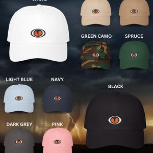 May include: A collection of 10 baseball caps in various colors, including white, stone, khaki, green camo, spruce, light blue, navy, black, dark grey, and pink. Each cap features a red and white eye graphic.