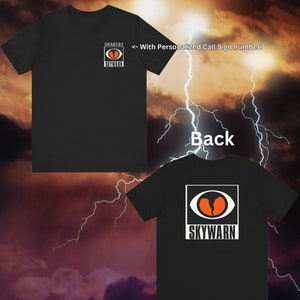 May include: Black t-shirt with a white square on the back featuring a red and white eye graphic with the text "SKYWARN". The front of the shirt has a smaller version of the graphic with the text "ORA9283" above it and "<-- With Personalized Call Sign number." below it.