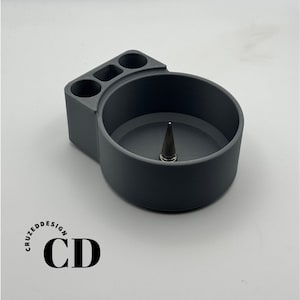 May include: Gray 3D printed organizer with three compartments and a round center section. The organizer has a small, pointed metal piece in the center.