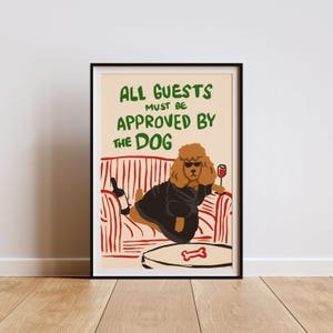 Puede incluir: Una impresión enmarcada con fondo blanco y un sofá a rayas rojas y blancas. Un caniche marrón con gafas de sol y una bata negra se sienta en el sofá sosteniendo una copa de vino tinto. El texto de la impresión dice "Todos los invitados deben ser aprobados por el perro."