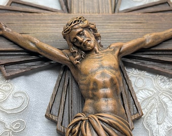 May include: A wooden crucifix with a brown and gold finish. Jesus is depicted with a crown of thorns and a cloth draped around his waist. The inscription "INRI" is visible on the cross.
