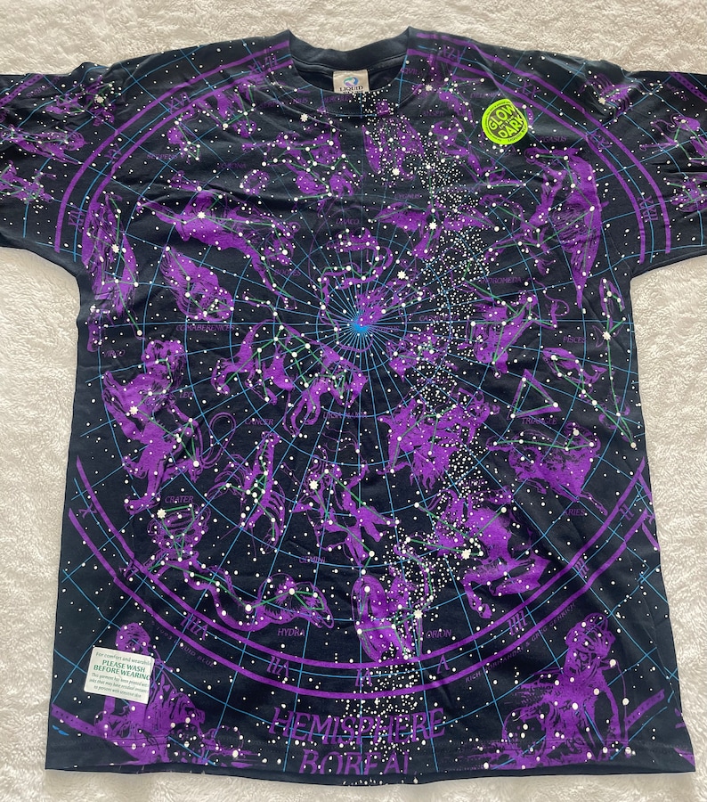 May include: A black t-shirt with a purple and blue constellation print. The shirt has a "Glow in the Dark" label and the text "Hemisphere Bor&eacute;al" at the bottom.