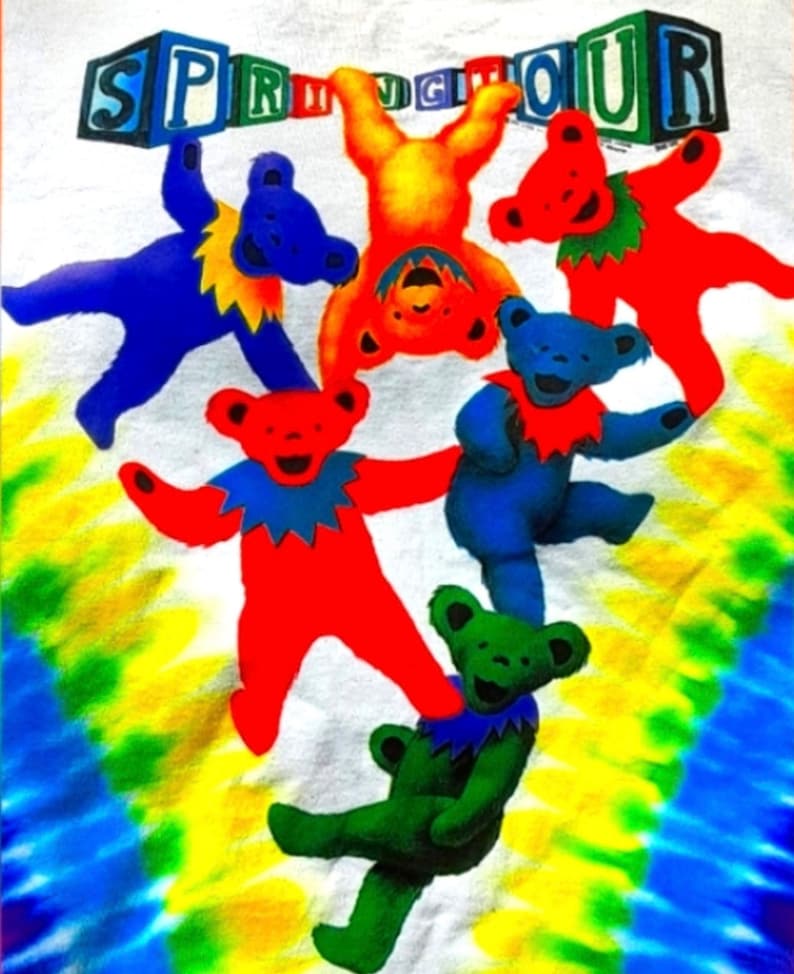 Puede incluir: Una camiseta tie-dye con un gr&aacute;fico colorido de osos bailando sosteniendo la palabra "SPRINGTOUR".