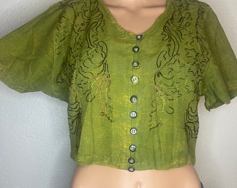 May include: A green short-sleeved button-up shirt with a floral design. The shirt is cropped and has a v-neck.