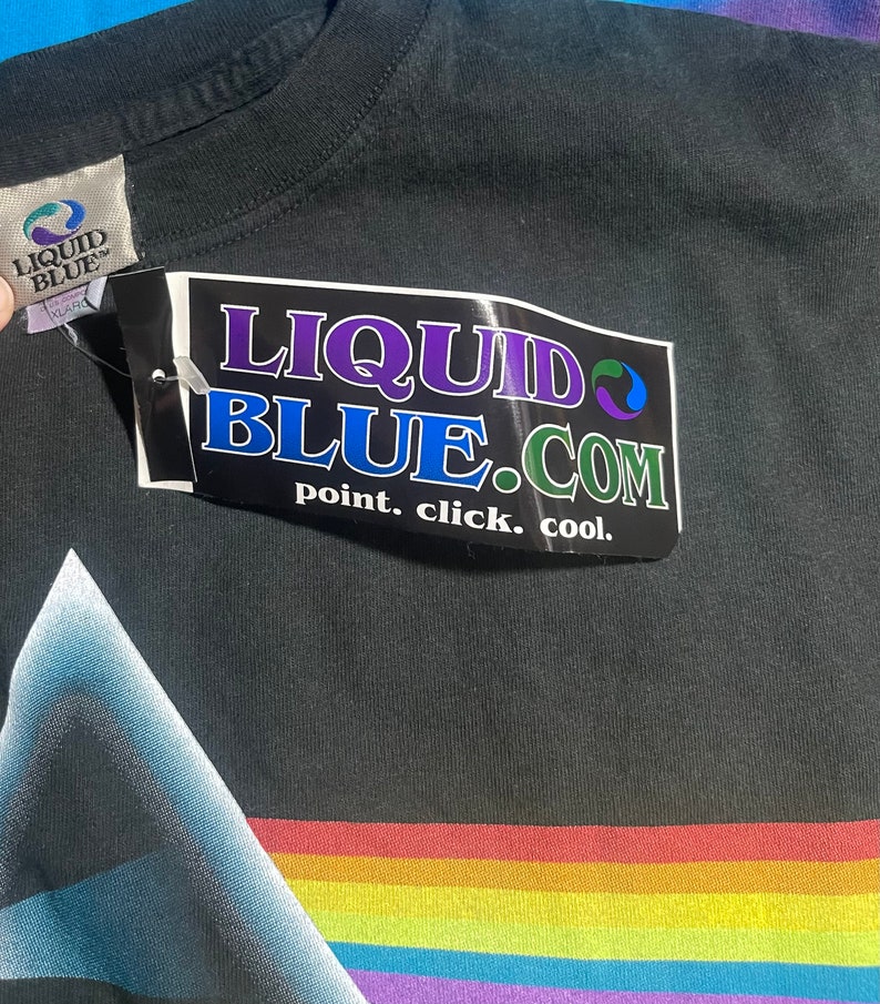 May include: Black t-shirt with a rainbow stripe design and a Liquid Blue tag. The tag says "point. click. cool."
