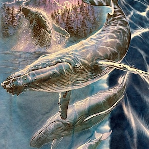 May include: A blue t-shirt with a detailed illustration of humpback whales in the ocean. The design includes whales breaching the water's surface, a forest, and a lightning storm in the background. The whales are depicted in shades of grey and blue.