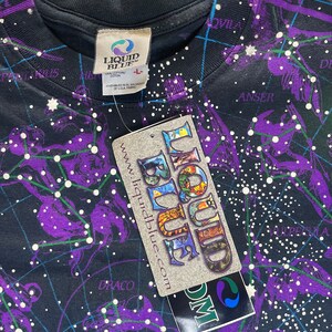 May include: A black t-shirt with a constellation print. The shirt features a purple and white design with the text "Liquid Blue" and "www.liquidblue.com".