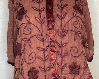 May include: A brown sheer button-up blouse with embroidered floral details and a satin trim down the front.