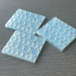 May include: Three stacks of clear adhesive dots, each stack containing multiple sheets of dots. The dots are designed for use with crafts, home decor, and other projects.