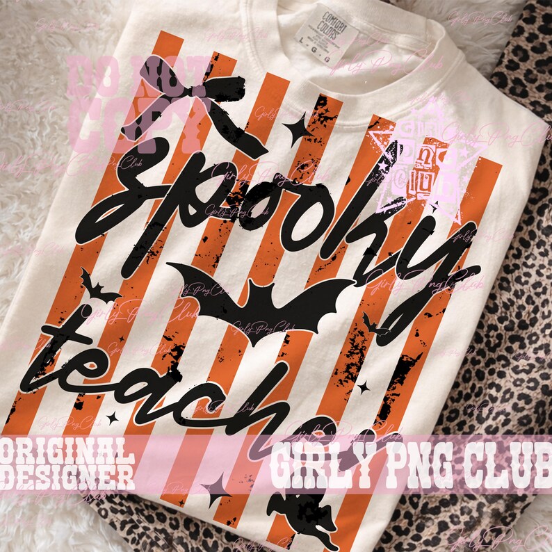 May include: A cream-colored t-shirt featuring vertical orange stripes and black distressed text that reads Spooky Teacher. The design includes a black bow, a central bat silhouette, small stars, and a witch graphic at the bottom hem.