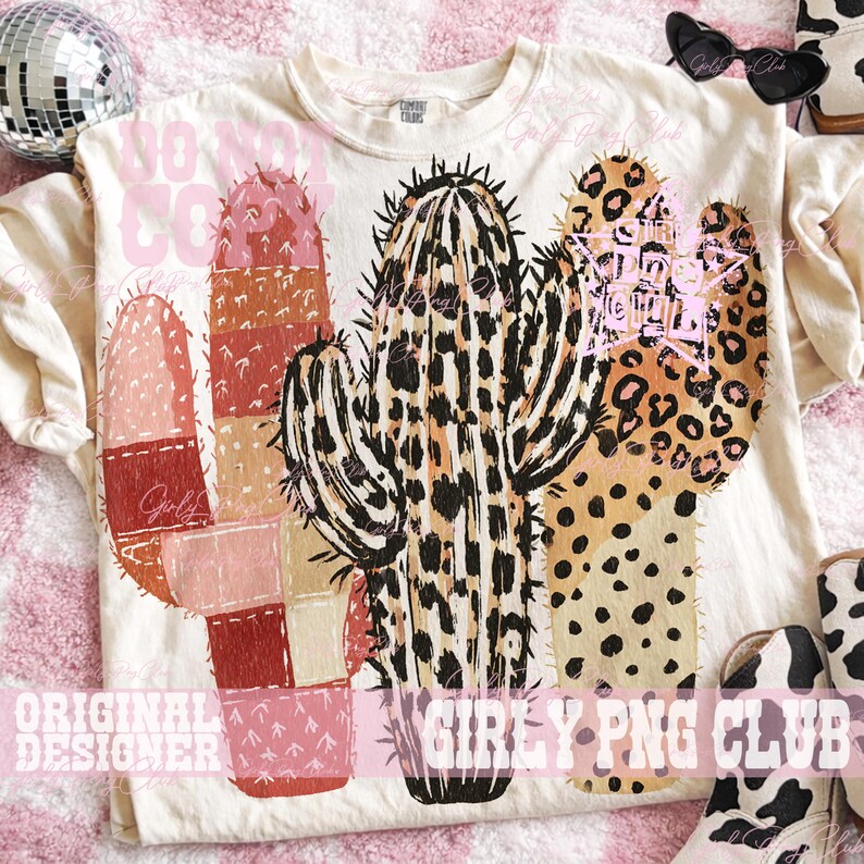 May include: Cream-colored t-shirt featuring a colorful cactus design. The cactus has a patchwork design with shades of pink, brown, and tan, and a leopard print pattern. The shirt also has text that reads "DO NOT CO".