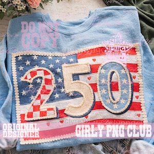 May include: Light blue sweatshirt with a large, patriotic design. The design features the numbers "250" in a textured, off-white material, set against a backdrop of the American flag. The flag design includes stars, stripes, and a decorative border.