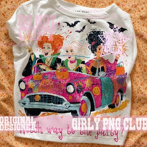 May include: A white t-shirt featuring a graphic of three women with distinct hairstyles riding in a bright pink vintage car. The design includes bats, pumpkin buckets, and the text "Which way to the party?" in pink script at the bottom of the shirt.