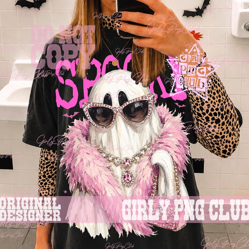 May include: A black t-shirt featuring a graphic of a white ghost wearing pink rhinestone cat-eye sunglasses, a pink feather boa, a silver-toned crystal necklace with a pink pendant, and holding a small pink glittery handbag.