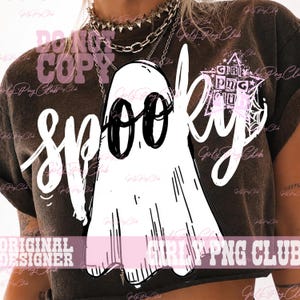 Puede incluir: Una camiseta de manga corta de color marr&oacute;n oscuro con un gran gr&aacute;fico blanco de un fantasma con ojos negros. La palabra "spooky" est&aacute; escrita en letra blanca sobre el fantasma. A la derecha se ve un logotipo en forma de estrella con el texto.