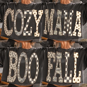 Puede incluir: Una sudadera de manga larga en gris carbón con letras grandes de bloque con patrones variados. La fila superior muestra el texto COZY MAMA, mientras que la fila inferior muestra el texto BOO FALL. Cada letra presenta un estampado de leopardo, camuflaje, cuadros o lunares.