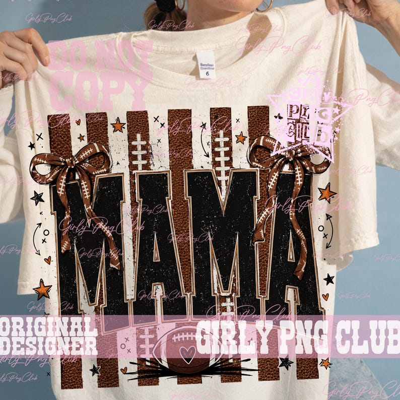 May include: A cream-colored t-shirt featuring a graphic design with the word MAMA in large black letters. The design includes brown football-textured vertical stripes, two brown bows, small orange stars, and a football icon at the bottom.