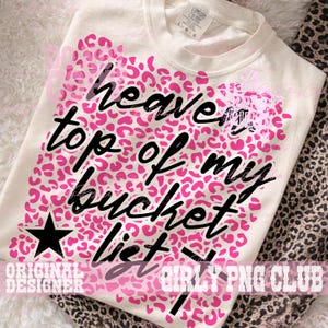 Peut inclure: T-shirt cr&egrave;me avec un motif l&eacute;opard rose et le texte noir "heaven top of my bucket list". Une &eacute;toile noire est &agrave; gauche. Le t-shirt a un col rond et des manches courtes.