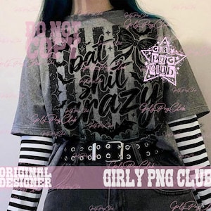 May include: A heather gray short-sleeve t-shirt featuring a black graphic print of bats, stars, a bow, and the text "bat shit crazy" in a stylized script font. The shirt is layered over a long-sleeve black and white striped shirt and a black belt.