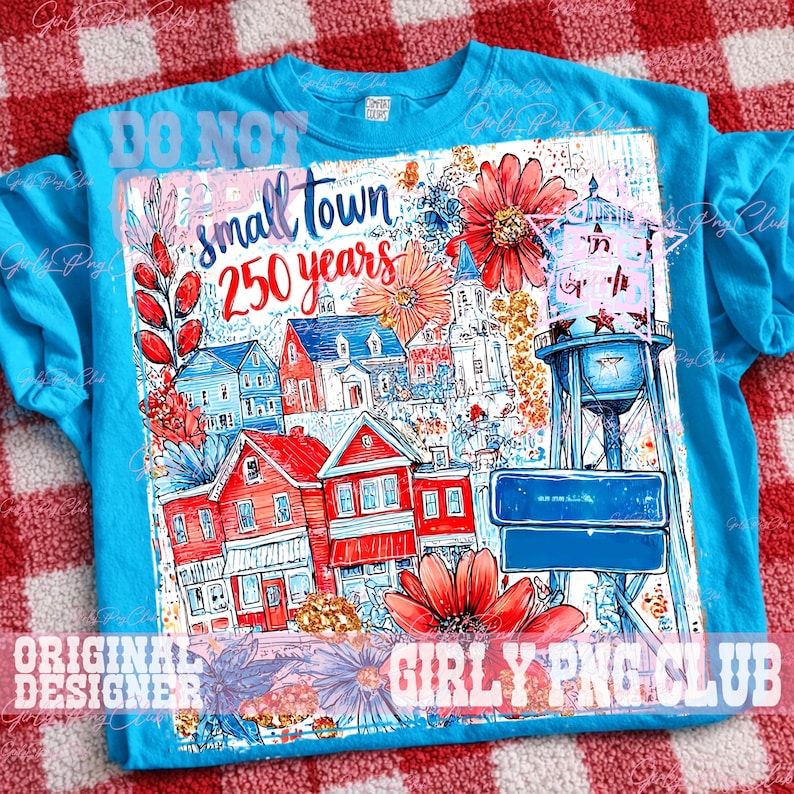 May include: A turquoise t-shirt with a vibrant illustration of a small town, including red and blue houses, a water tower, and flowers. The text "small town 250 years" is printed on the front.