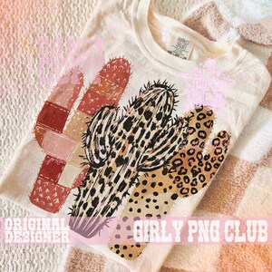 May include: Cream-colored t-shirt featuring a colorful cactus design. The cactus has sections with patchwork, leopard print, and black spiky details. The text "ORIGINAL DESIGNER" and "GIRLY PNG CLUB" are printed on the bottom of the shirt.