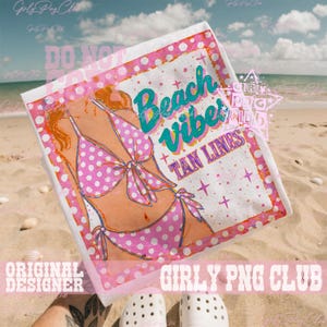 May include: A white beach towel with a pink polka dot bikini design and the words "Beach Vibes Tan Lines" in teal and purple. The towel has a pink border with white polka dots and is on a sandy beach.