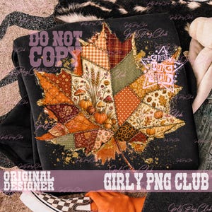 May include: A black sweatshirt featuring a large, central graphic of a maple leaf composed of various patchwork patterns in autumn colors, including orange, brown, and green. The leaf design incorporates illustrations of pumpkins and mushrooms.
