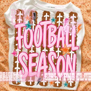 Peut inclure: Un t-shirt blanc avec une impression graphique de lacets de ballon de football marron et le texte FOOTBALL SEASON en grandes lettres roses. Le motif comprend des &eacute;toiles color&eacute;es et des &eacute;clairs orange, bleu sarcelle et rose sur le devant.