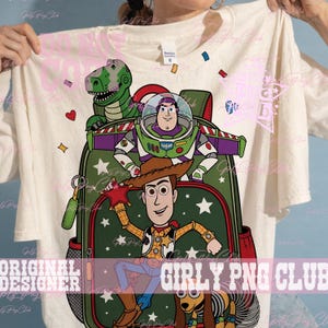 Puede incluir: Una camiseta color crema con un estampado gr&aacute;fico de una mochila verde decorada con estrellas blancas. El dise&ntilde;o incluye personajes de dibujos animados: un dinosaurio verde, un ranger espacial, un vaquero y un juguete de perro salchicha.