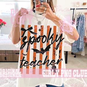May include: A white short-sleeved t-shirt featuring a graphic print of vertical orange and black distressed stripes. The design includes the black cursive text Spooky teacher, a black bow, a black bat silhouette, and a small ghost icon.