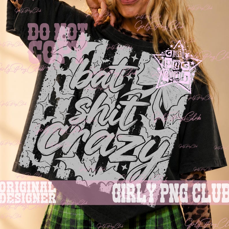 May include: A black short-sleeved t-shirt featuring a large, distressed white graphic print. The design includes the text "bat shit crazy" in a bold, stylized font, surrounded by illustrations of bats, stars, and a bow, with a star-shaped logo containing the text "GIRLY PNG CLUB".