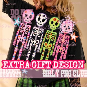 May include: A black t-shirt featuring a graphic of four colorful skeletons. The skeletons are pink, white, green, and pink, decorated with small patterns. The design includes a star shape with the text GIRLY PNG CLUB and the text EXTRA GIFT DESIGN.