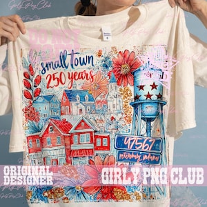 May include: Cream-colored t-shirt featuring a colorful illustration of a small town with red and blue houses, a water tower, and the text "small town 250 years". The design includes floral accents and the town's zip code.