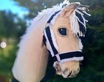 May include: A white and black horse head with a black halter and white fur trim. The horse head is made of plush fabric and has a realistic look.