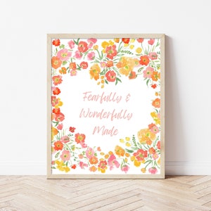 Puede incluir: Una impresión enmarcada con un diseño floral en tonos rosa, naranja y amarillo. El texto "Fearfully & Wonderfully Made" está escrito en el centro de la impresión.