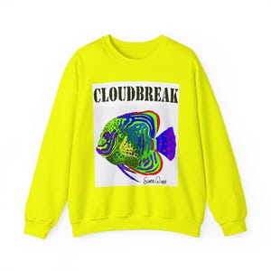 May include: A vibrant yellow sweatshirt with a graphic of a tropical fish. The fish is in green, blue, and red, with the word "CLOUDBREAK" above it. The artist's signature, "Scott West," is below the fish.