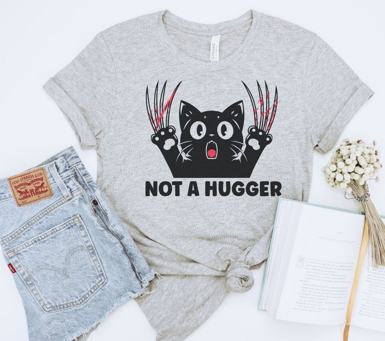 May include: Gray t-shirt with a black cat with red claws and the text "NOT A HUGGER".
