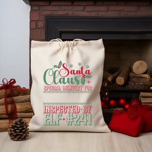 May include: A white canvas Santa sack with green and red text that reads "Santa Claus Special Delivery For Inspected By Elf #241".