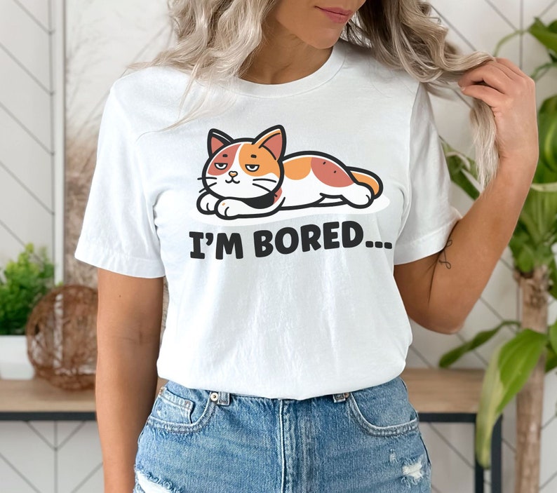 May include: White t-shirt with a cartoon cat lying down and the text "I'm Bored..." printed on it.