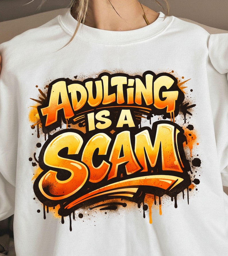 Pu&ograve; includere: Felpa bianca con la scritta "ADULTING IS A SCAM" in grandi lettere arancioni e gialle in stile graffiti. Il design include gocce e schizzi neri, creando un'affermazione audace e accattivante.
