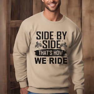 May include: Tan sweatshirt with black text that reads "Side by Side That's How We Ride" with a graphic of two side-by-side vehicles.