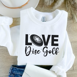 May include: White sweatshirt with black text that reads "LOVE Disc Golf" and a black disc golf disc with a white star in the center.