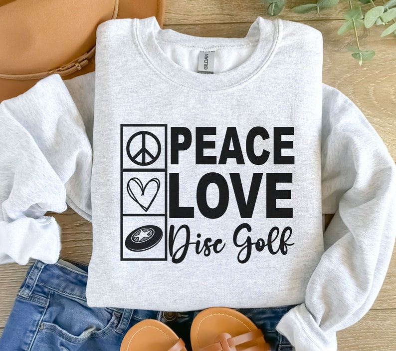 May include: A gray sweatshirt with the text "Peace Love Disc Golf" in black. The text is surrounded by three icons: a peace sign, a heart, and a disc golf disc.