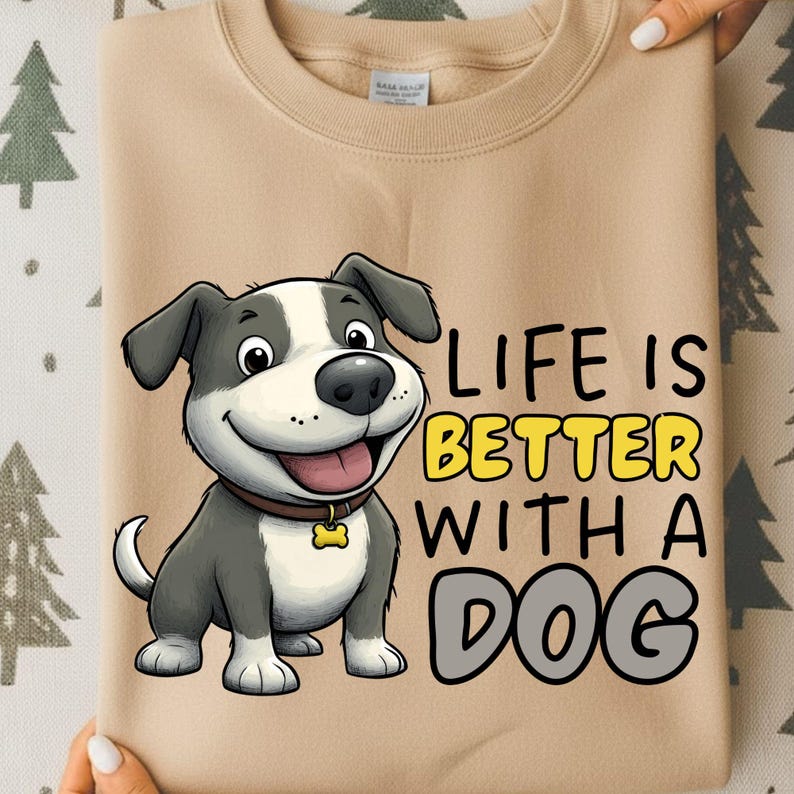 May include: Tan sweatshirt featuring a cartoon dog with a brown collar and a tag. The text "LIFE IS BETTER WITH A DOG" is printed in yellow and gray. The sweatshirt is a neutral color.