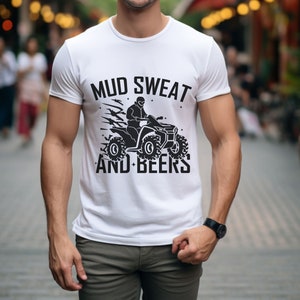 May include: White t-shirt with a black graphic of a person riding an ATV with the text "MUD SWEAT AND BEERS".