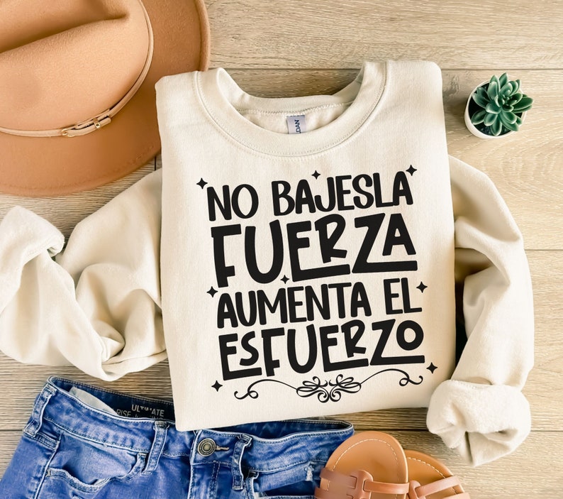 May include: A cream-colored sweatshirt with the text "No bajes la fuerza aumenta el esfuerzo" in black lettering.