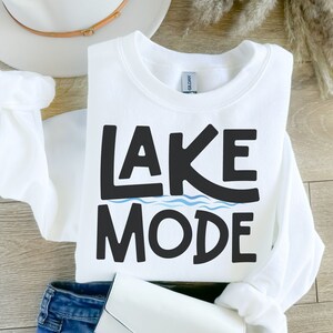 May include: White sweatshirt with black text that says "LAKE MODE" with a blue wavy line under the word "LAKE".