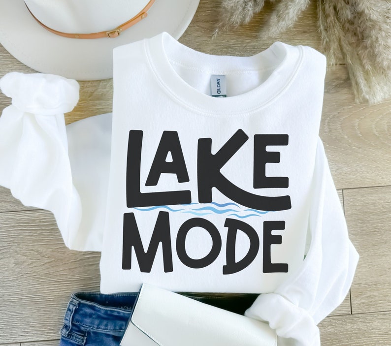 May include: White sweatshirt with black text that says "LAKE MODE" with a blue wavy line under the word "LAKE".